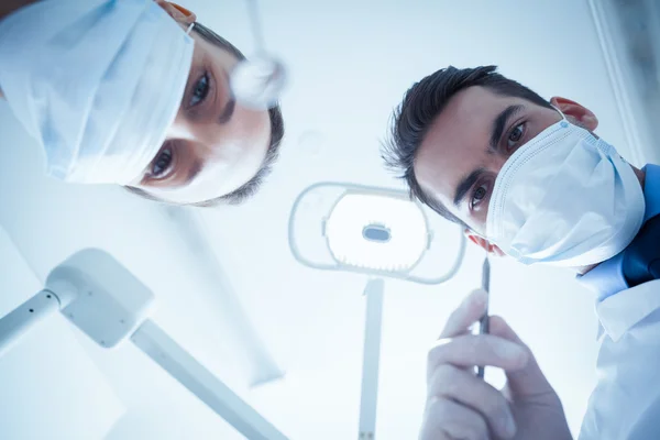 Dentists in surgical masks holding dental tools