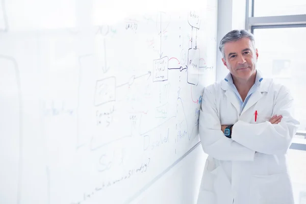 Smiling scientist leaning against the whiteboard