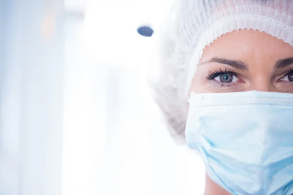 Dentist in surgical mask and cap looking at camera