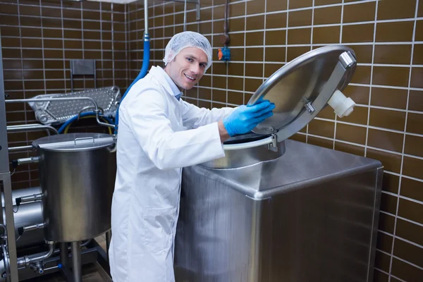 Smiling man in lab coat opening the lid of the machine