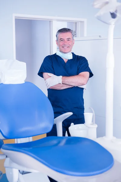 Dentist in blue scrubs beside chair