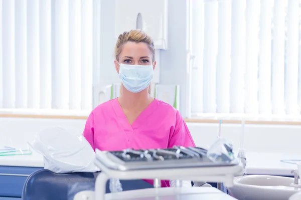 Dentist in mask wearing pink scrubs
