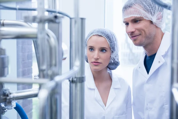 Smiling scientist with colleague looking metal gauge