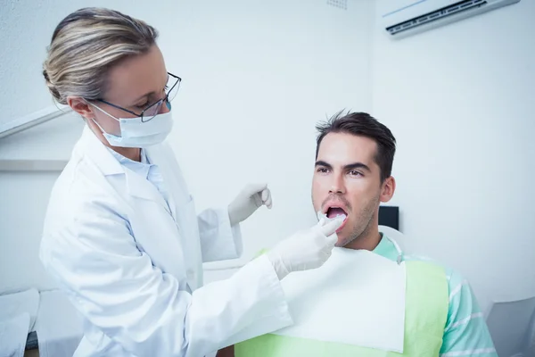 Female dentist examining mans teeth