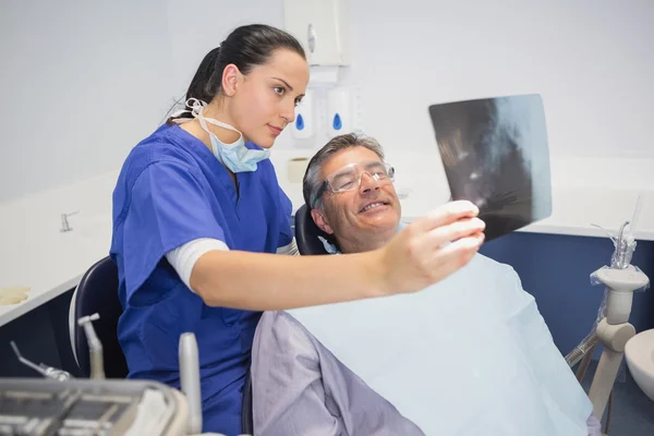 Smiling dentist showing x-ray to her patient