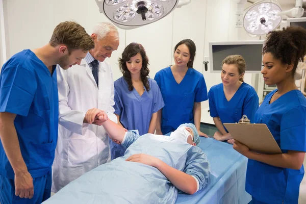 Medical students and professor checking pulse