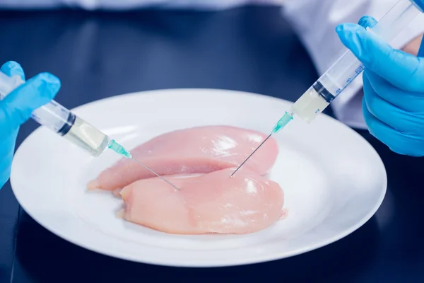 Food scientist injecting raw chicken