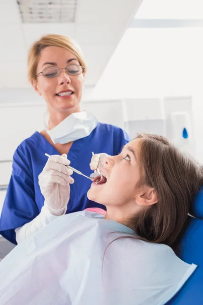 Smiling pediatric dentist examining her young patient