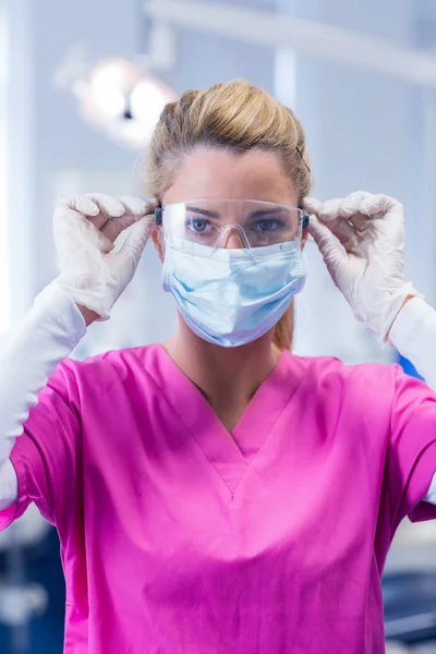 Dentist in pink scrubs in mask and gloves