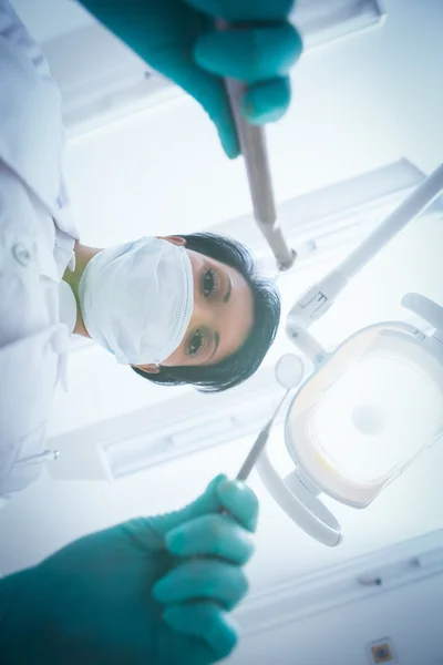 Female dentist in surgical mask holding dental tools