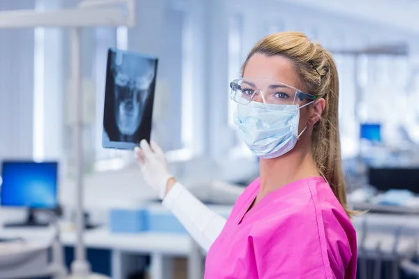 Dentist in pink scrubs holding an x-ray