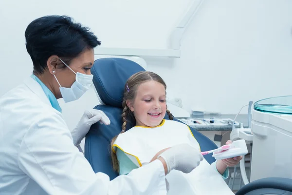 Dentist teaching girl how to brush teeth