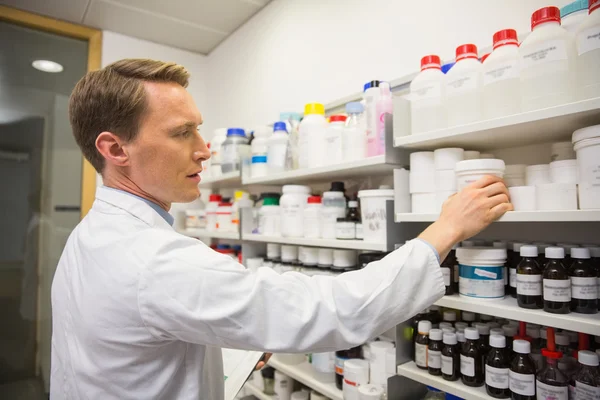 Handsome pharmacist taking medicine from shelf