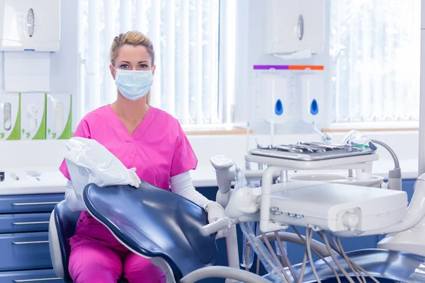 Dentist in pink scrubs beside chair