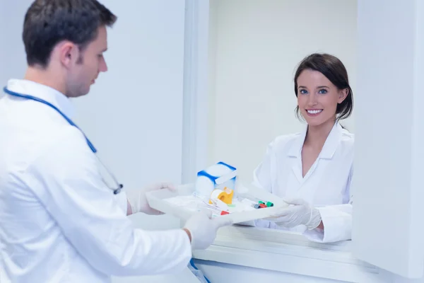 Portrait of a smiling woman taking tray with blood samples