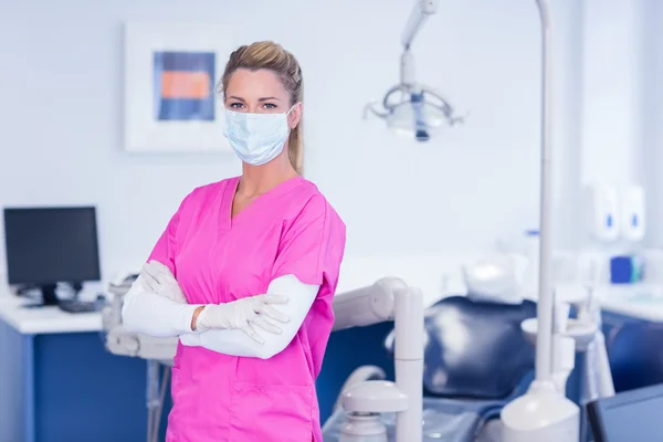 Dentist in pink scrubs with arms crossed