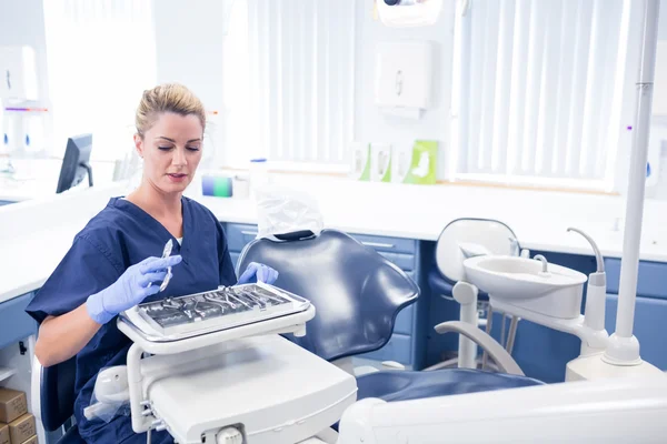 Smiling dentist sitting with tray of tools