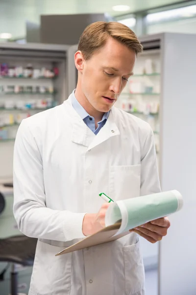 Focused pharmacist writing on clipboard