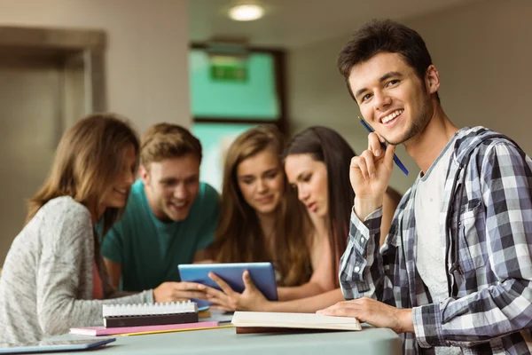 Smiling friends sitting studying and using tablet pc