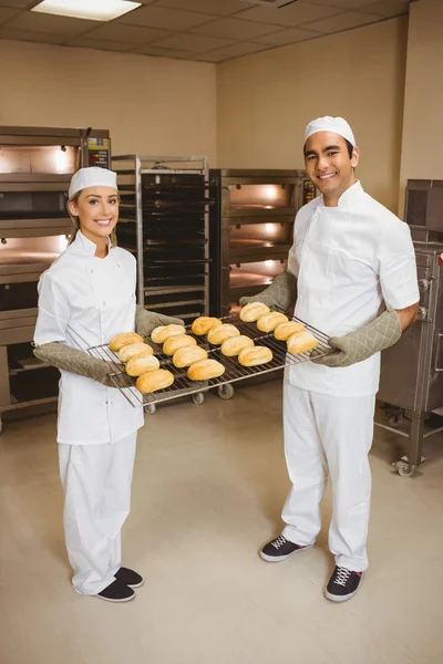 Team of bakers holding rack of rolls