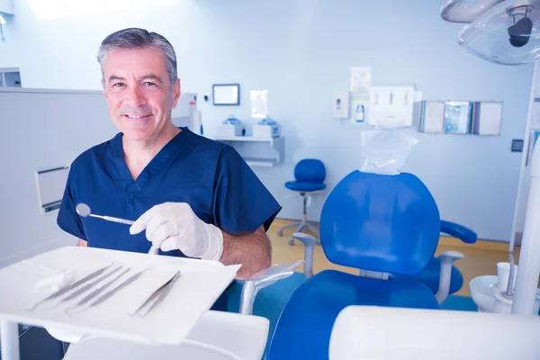 Dentist in blue scrubs holding tools