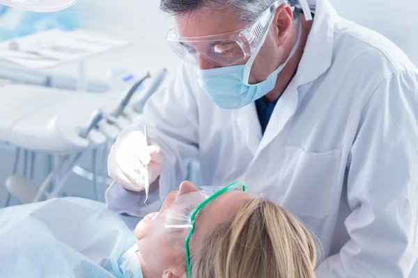 Dentist in surgical mask and gloves holding tool