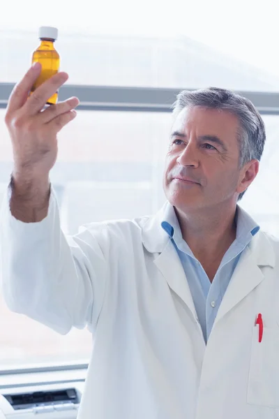 Scientist in lab coat holding a chemical bottle