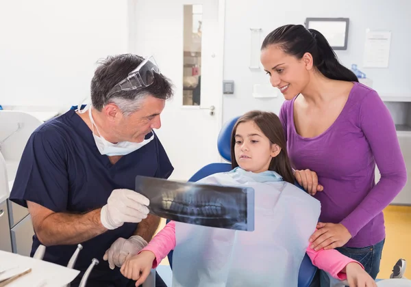 Pediatric dentist explaining to young patient
