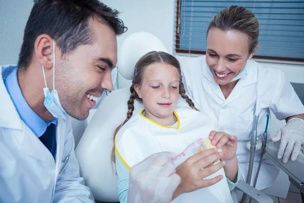 Dentist with assistant teaching girl