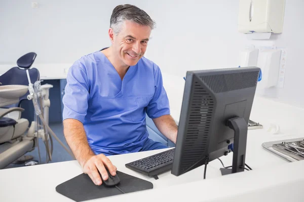 Portrait of a happy dentist using computer