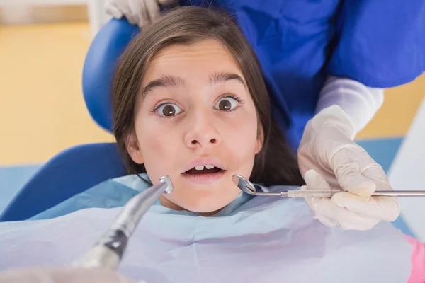 Dentist and his dental assistant examining a terrified young pat