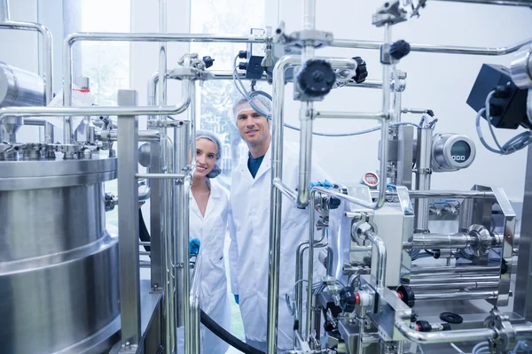 Scientist team behind metal gauge looking at camera