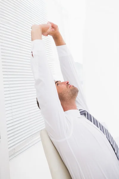 Businessman stretching in swivel chair