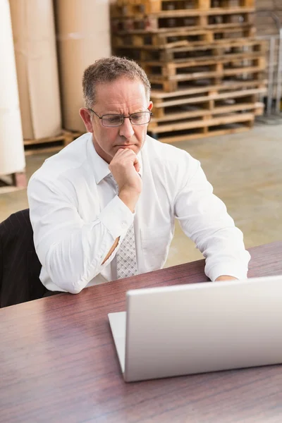 Serious warehouse manager using laptop