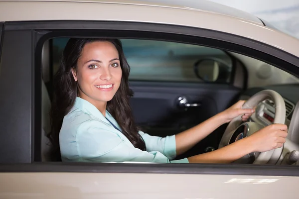 Smiling customer sitting at the wheel of a car for sale