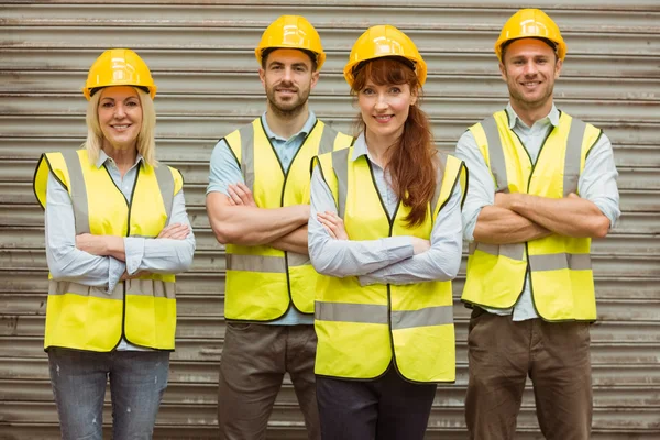 Warehouse team with arms crossed wearing hard hat