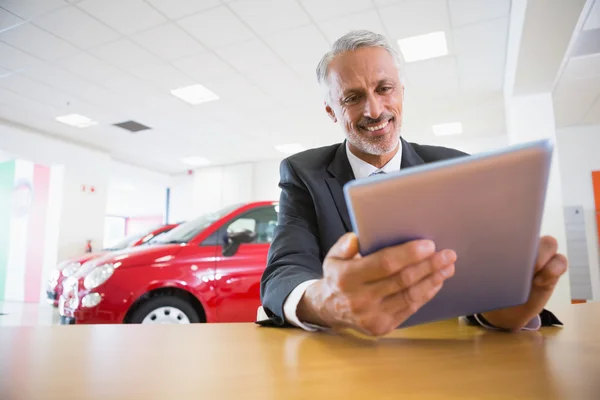 Smiling businessman using tablet at his desk