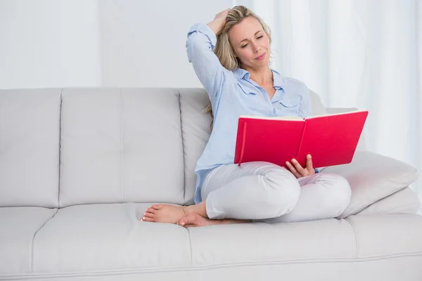 Calm blonde on couch reading notebook