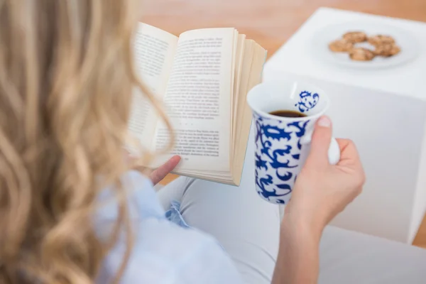 Blonde reading with cup of coffee
