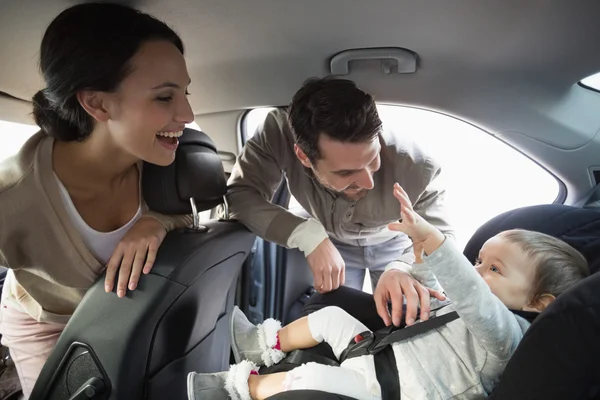 Parents securing baby in the car seat