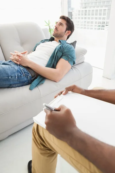 Man lying on sofa talking to therapist