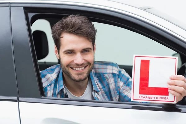 Learner driver smiling and holding l plate