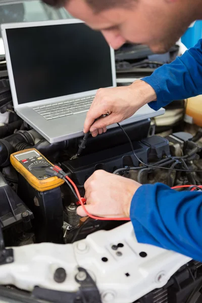 Mechanic using diagnostic tool on engine