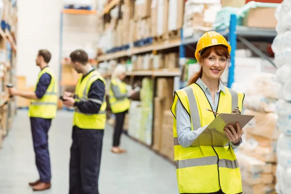 Smiling warehouse manager holding clipboard