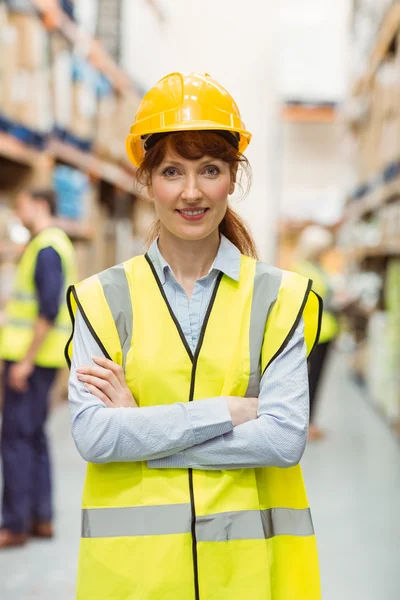 Warehouse manager smiling at camera with arms crossed