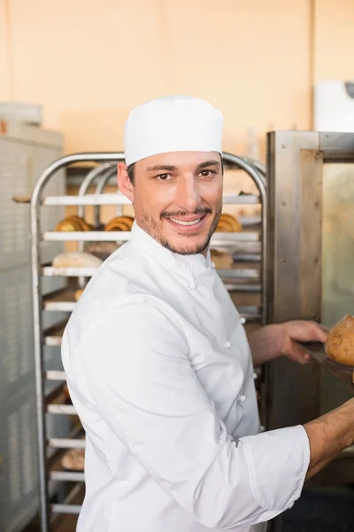 Happy baker taking out fresh loaves