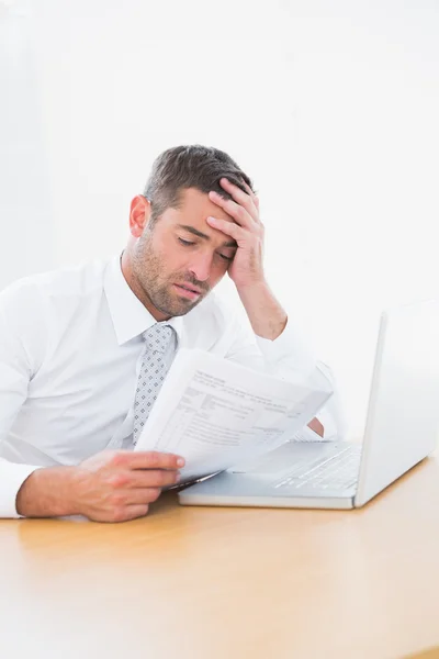 Confused businessman looking at his paper