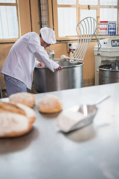 Baker preparing dough in industrial mixer