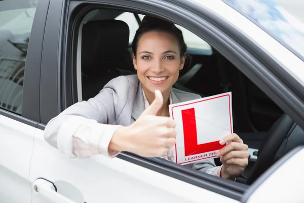 Female driver giving thumbs up while holding her L sign