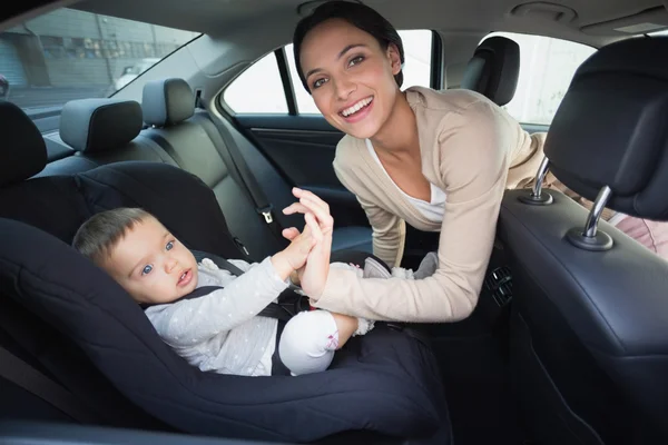 Mother securing her baby in the car seat